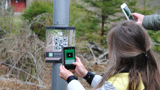 Person som skannar en QR-kod som sitter på en lyktstolpe.