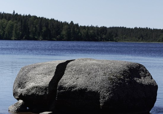 Stor sten som ligger i en sjö. Stenen är delad på mitten.
