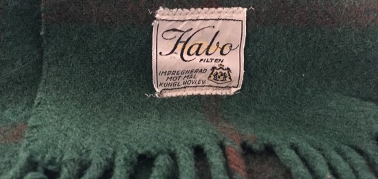 Grön ullfilt med en etikett som det står Habo-filten på.