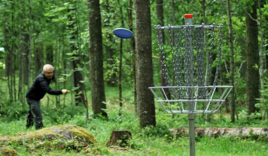 En man som spelar discgolf i en skog.