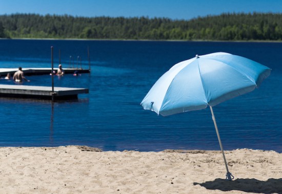 Blått parasoll på en sandstrand.