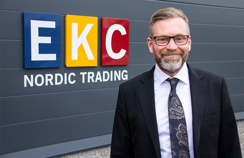 VD Magnus Brukén, iklädd mörk kostym, står bredvid en skylt där det står EKC Nordic Trading.