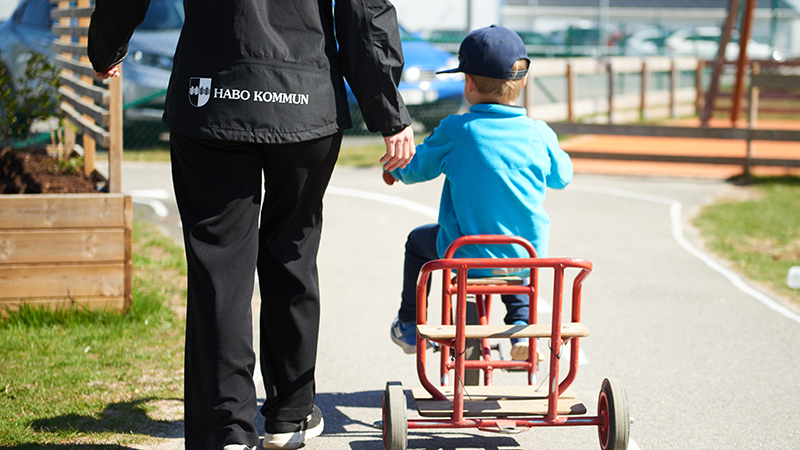 En pedagog som går bredvid ett barn som cyklar.