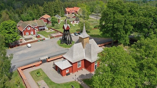 Brandstorps kyrka, röd kyrkobyggnad och röd klockstapel med omkringliggande röd trähusbebyggelse.